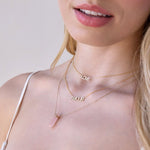 A close-up of a blonde woman's neck wearing a yellow gold LOVE Necklace, AMOUR Necklace and The Love Retreat Necklace. 
