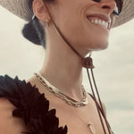 Abigail Spencer wearing a yellow gold Bold Link Chain, Sequence Chain and two Retreat Necklaces in Clarity and Love,  with a straw hat, sunglasses and a black top with a white blurred background. 