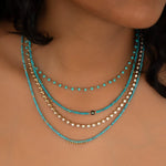 Close-up of a neck wearing The Bluebell Bouquet Necklace, Endless Summer Necklaces in Turqs + Caicos and Santorini, and The Ultimate Diamond Necklace.