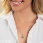Close-up of a blonde woman wearing a Zodiac Necklace - Leo with a white shirt against a neutral background. 