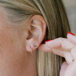 Close-up of a Lip Stud and Thin Gold Hoop in a blonde woman's ear. 