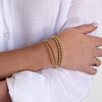 A woman’s arm wearing a Luxe Bubble Bracelet Set with a white linen shirt. 