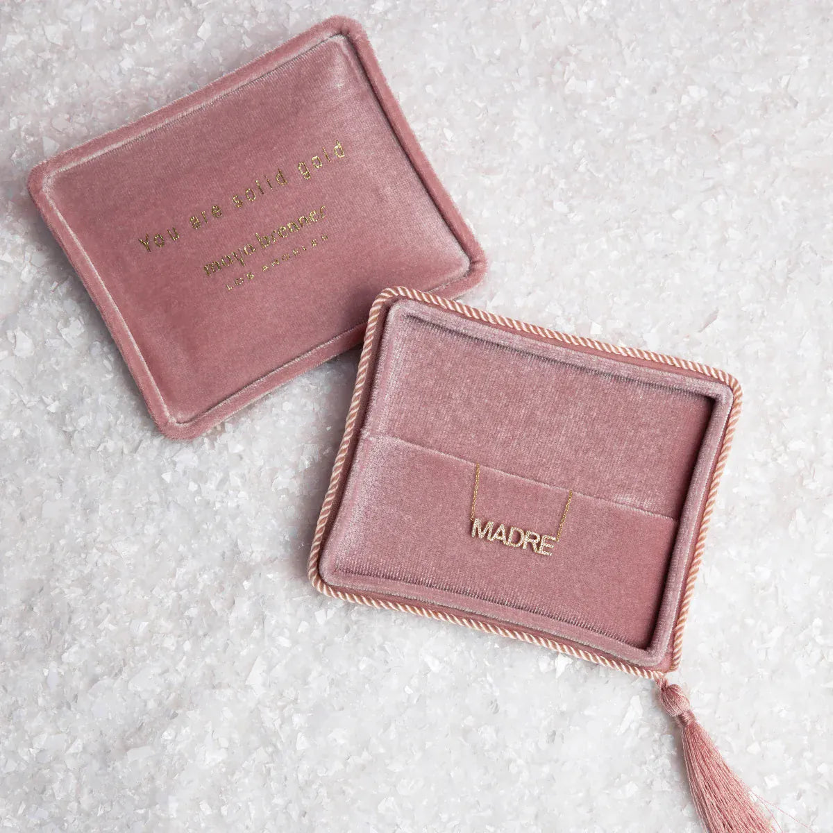 Two pink velvet jewellery boxes with a Pavé Madre Necklace on a textured off-white background. 
