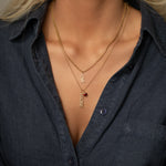 Close-up of a person wearing layered gold necklaces with visible text and a red gemstone.