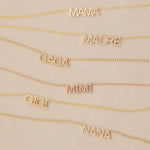 MAMA, Pavé MADRE, Pavé GAGA, Pavé MIMI, GIGI and Pavé NANA Necklaces in yellow or rose gold laid against a light beige background. 