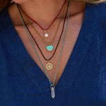 Close-up of a person wearing multiple necklaces with pendants on a blue background