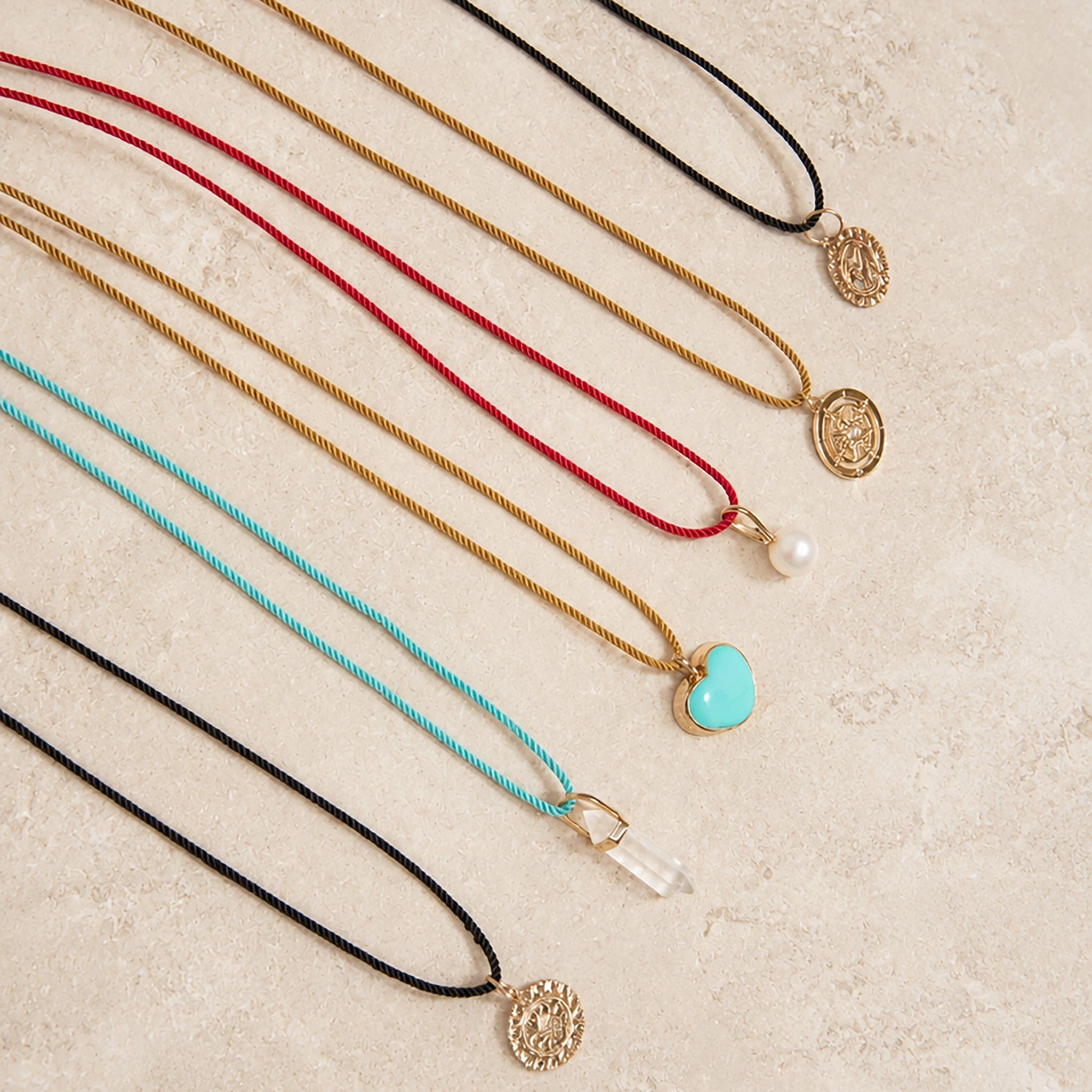 Set of necklaces with various Color Cored Necklaces with pendants on a textured surface