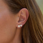 Close-up of an ear wearing two diamond stud earrings with blurred background