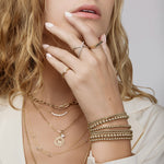 Close-up of a woman's hand wearing gold jewelry including rings, bracelets, and necklaces.