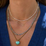 Khaki Color Cord Necklace with turquoise heart pendant worn by a person in a blue shirt.