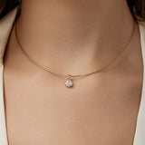 Gold necklace with a diamond pendant on a person wearing a white shirt.