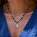 Close-up of a person wearing two necklaces with a blue garment in the background
