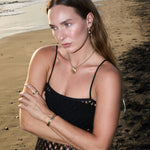 Model wearing Maya Brenner Soleil Hoops with pearl earring charms, styled with gold shell pendant necklace and gold cuff bracelet on the beach