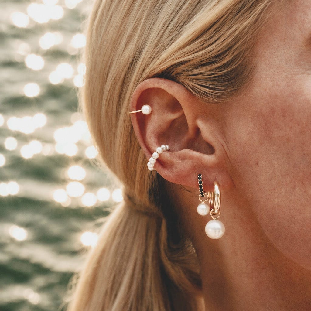 Model wearing Maya Brenner Soleil Hoops styled with pearl earring charms and pearl ear cuff, layered ear stack with gold hoop earrings