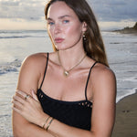 Model wearing Maya Brenner Soleil Hoops with pearl earring charms and gold shell necklace on rolo chain, styled at the beach