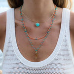 Model wearing the Balance Crystal Charm on a turquoise beaded necklace with colorful layered necklaces.