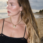 Model wearing Maya Brenner Soleil Hoops with Mini Pearl Ear Charms and a gold shell pendant necklace.
