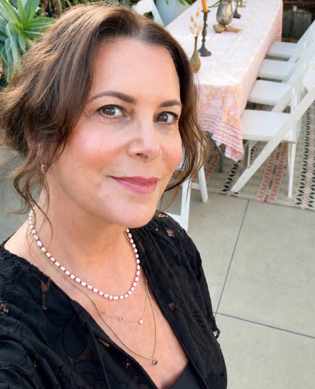 Maya Brenner wearing the Cabana Pearl Necklace layered with delicate gold necklaces at an outdoor gathering