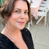 Maya Brenner wearing the Cabana Pearl Necklace layered with delicate gold necklaces at an outdoor gathering
