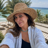 Woman wearing a straw hat with a beach and ocean view in the background