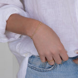 Close-up of a woman’s arm wearing a Mini Bubble Bracelet, two Delicate Beaded Bands and a Twinkle Twinkle Ring, with a white shirt and light blue jeans.
