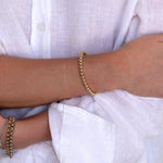A close-up of arms wearing mixed metal bracelets - a Luxe Bubble Bracelet, two Rolo Bracelets and two Diamond Cut Bracelets. 