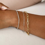 A close-up of a wrist wearing a white gold Down the Line Bracelet, a white gold Element Long Link Bracelet and a yellow gold Bold Link Bracelet. 