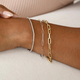A close-up of a wrist wearing a white gold Down the Line Bracelet, a white gold Element Long Link Bracelet and a yellow gold Bold Link Bracelet. 