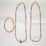 Endless Summer Necklaces in Coral Reef and Sweet Escape and an Endless Summer Bracelet in Coral Reef on a cream fabric background.