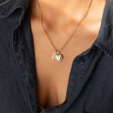 14k gold MUM word plate charm necklace styled with heart locket pendant on model.