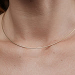 Close-up of a thin gold necklace on a person's neck