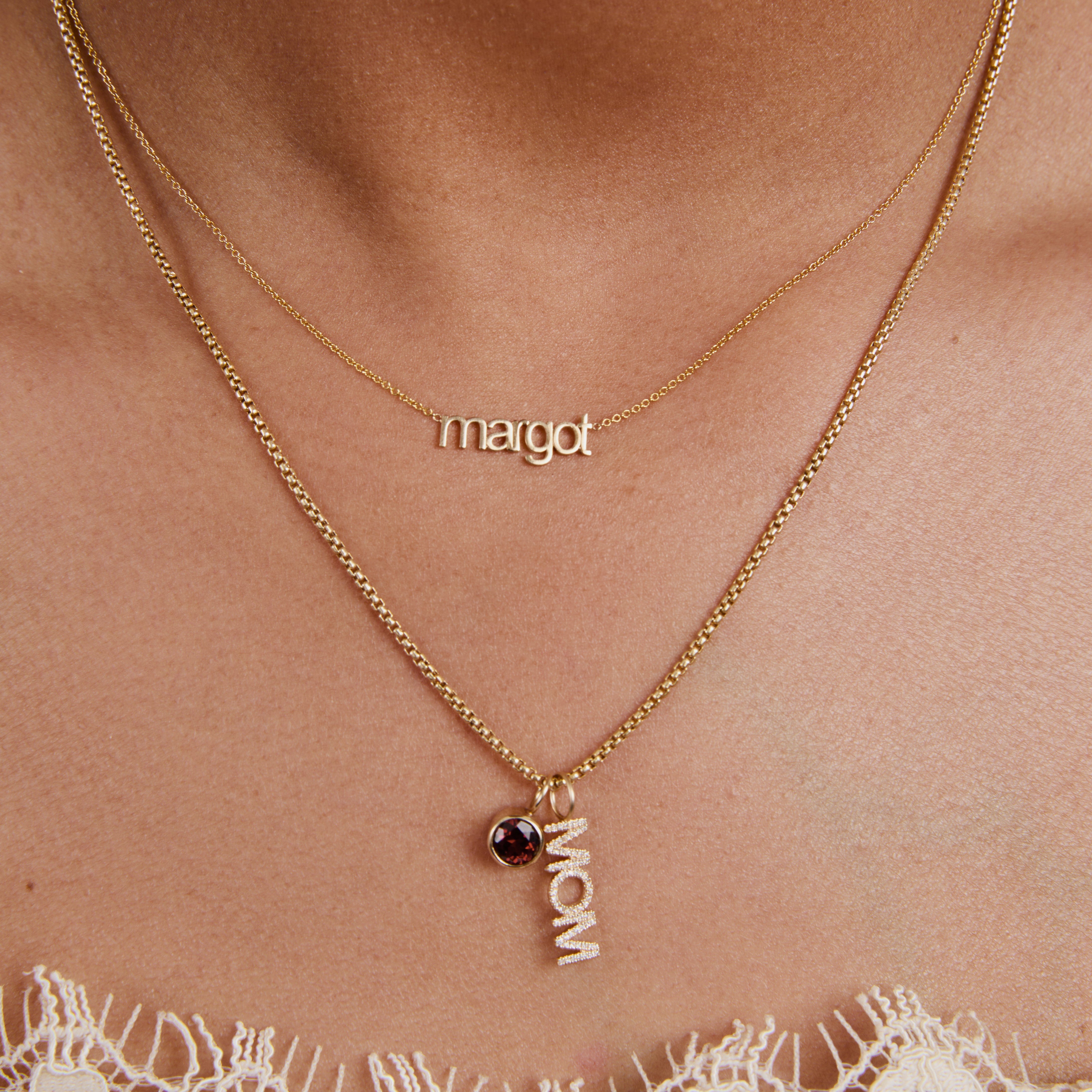 Gold necklace with 'margot' and 'mom' pendant on a person's neck