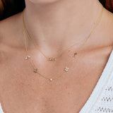 Gold necklace with 'olivia' pendant on a person wearing a white top.
