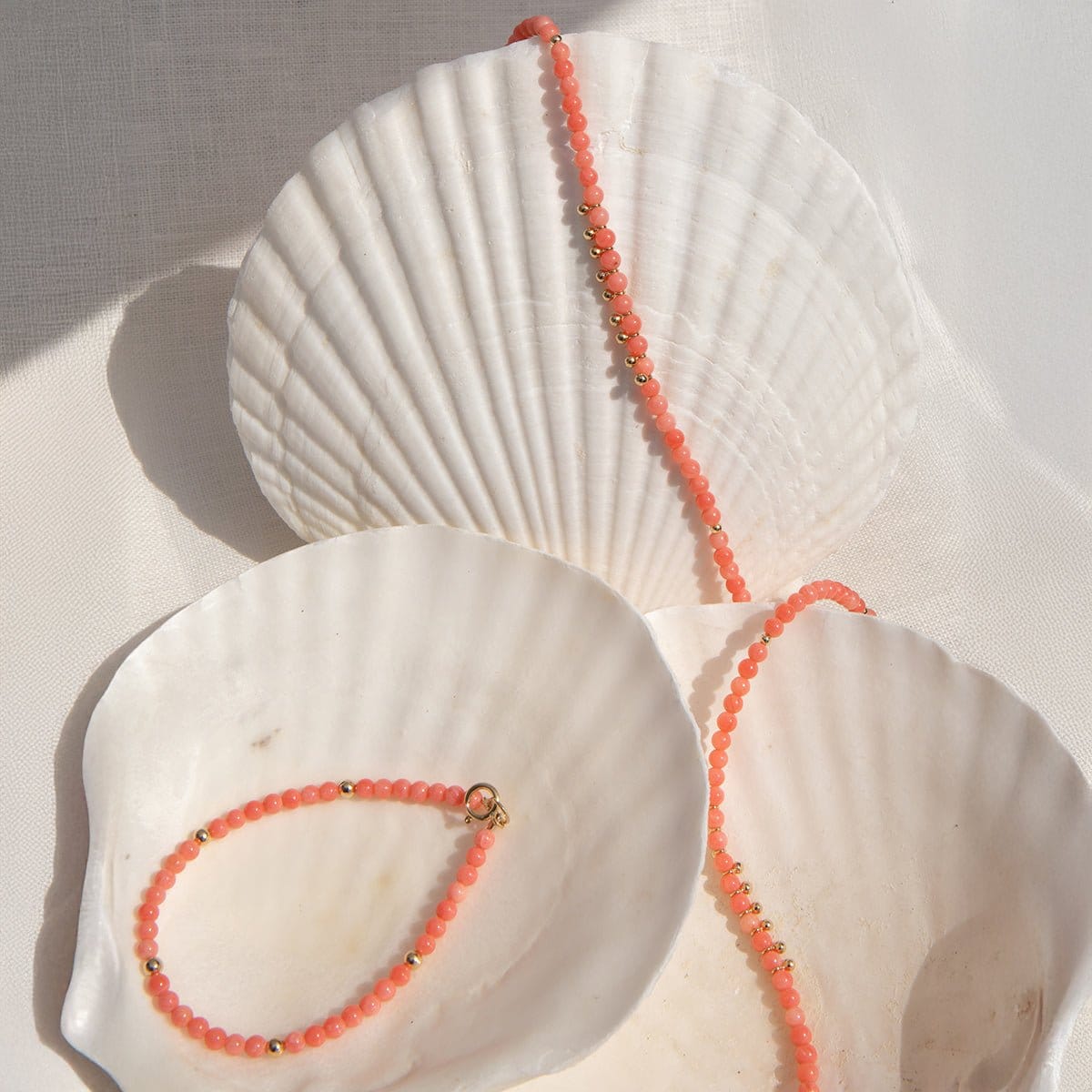 An Endless Summer Bracelet and Necklace in Mykonos laid on three big white shells against a white fabric background. 
