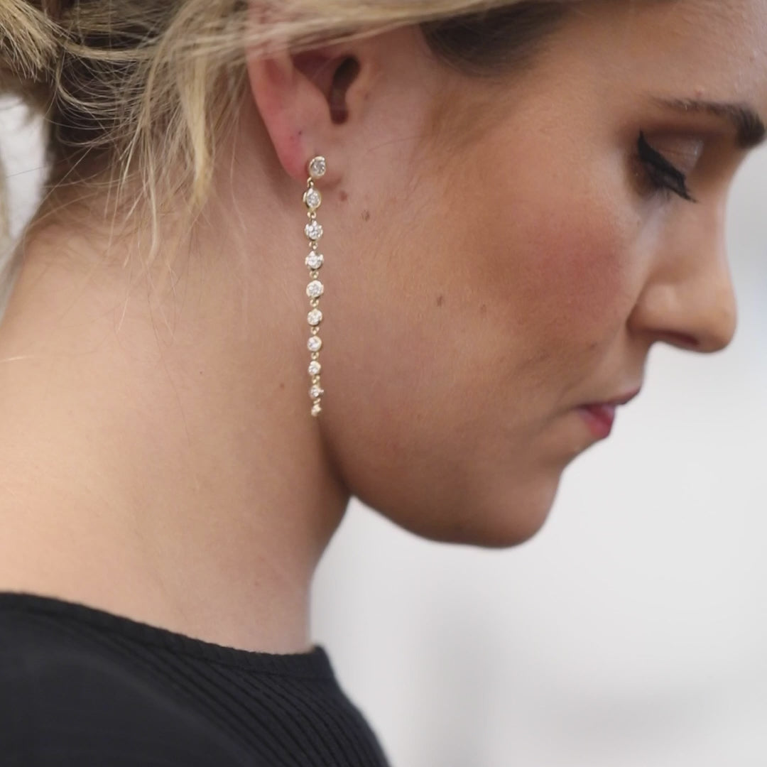A close-up of a woman wearing a Diamond Cascade Earring, with blonde hair and a black top.