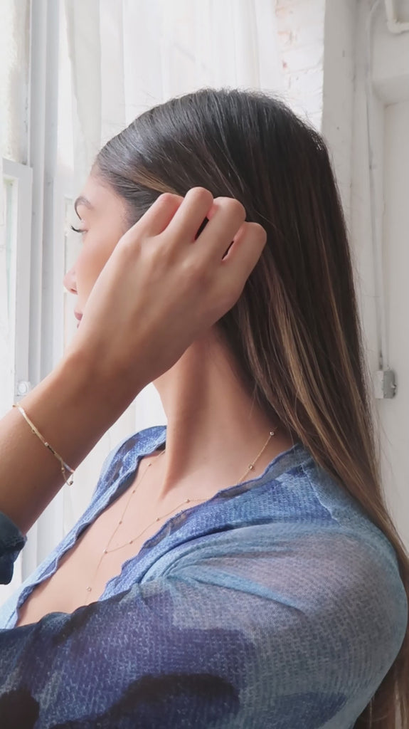 A video of a woman wearing a Starstruck Diamond Lariat Necklace and Bracelet and an Off the Cuff Bracelet, all in yellow gold, styled in a blue dress. 
