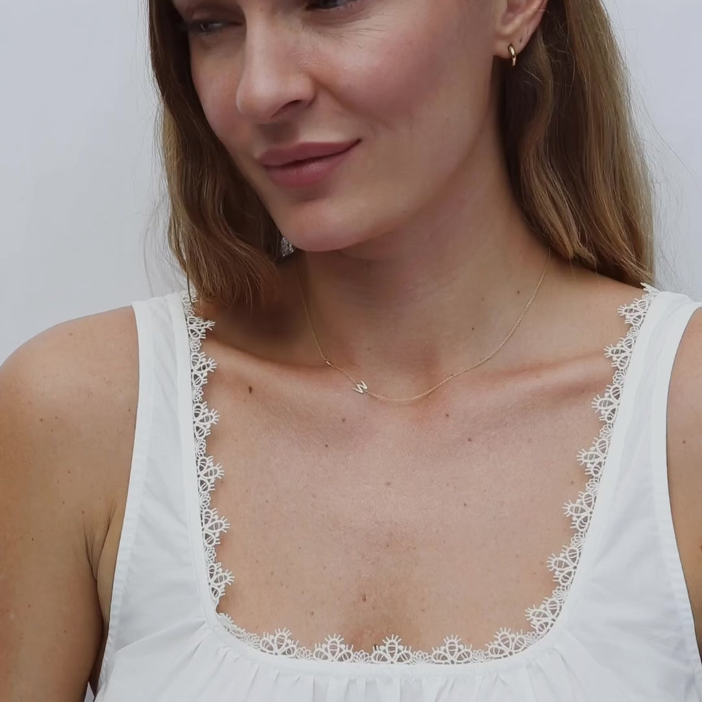 video of woman wearing delicate 2 letter gold necklace on white background