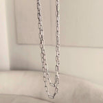 A video of two white gold Bold Link Chains dangling with a neutral background. 