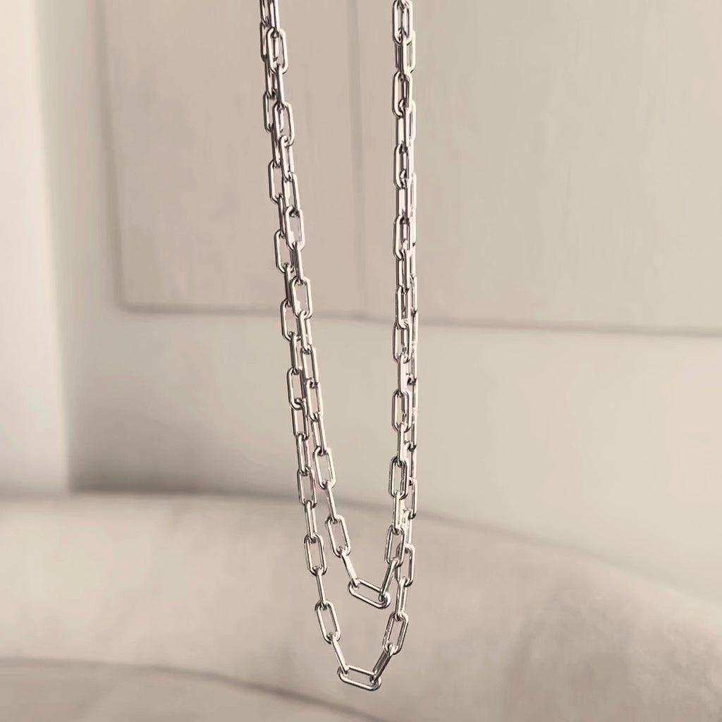 A video of two white gold Bold Link Chains dangling with a neutral background. 