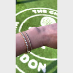 A video of a Love Set Match Bracelet and Down the Line Bracelet against a Wimbledon green grass background. 