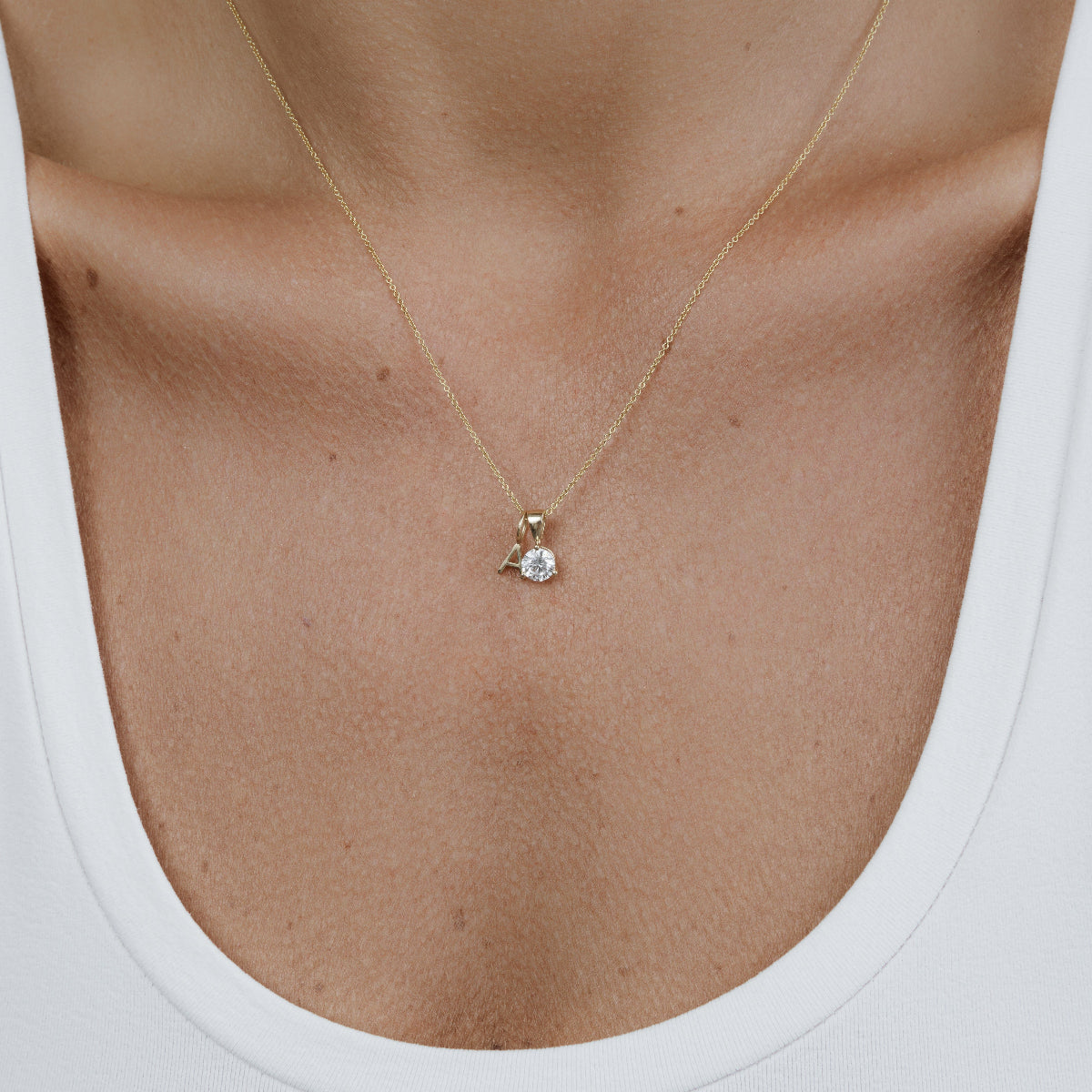 A decellotage wearing a Signature Cable Chain with a Princess Diamond Pendant and a Gold Letter Charm in A, and a white top. 