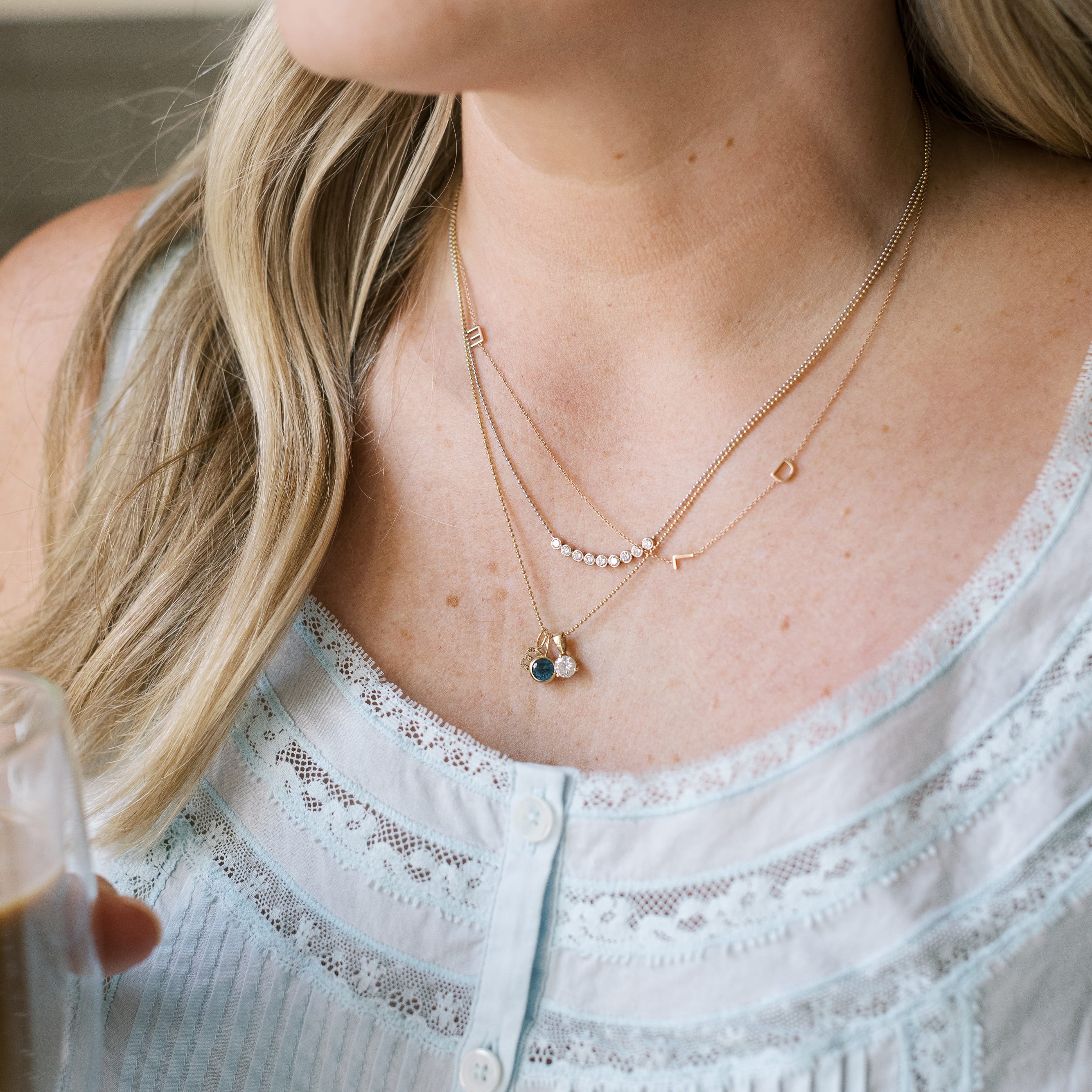 Close-up of a person wearing multiple gold necklaces with small pendants.