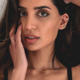 Woman with hand near face wearing a gold necklace