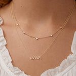 Necklace with 'MAMA' pendant on a person wearing a white top.