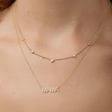 Gold necklace with 'MAMA' word plate and a five diamond necklace on a person's neck.