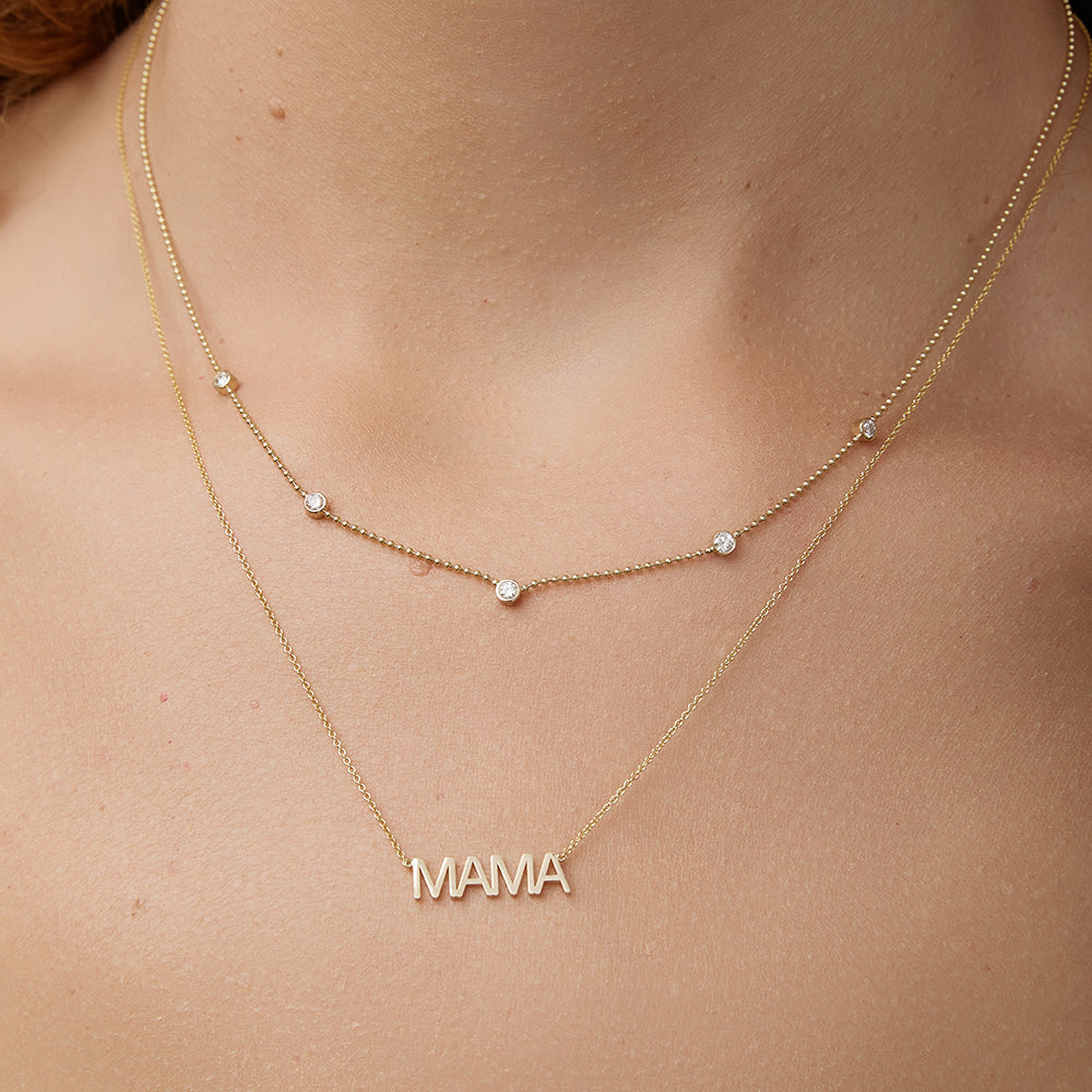 Gold necklace with 'MAMA' word plate on a person's neck