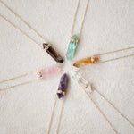 Five Retreat Necklaces (Courage, In Flow, Happiness, Clarity, Healing and Love) on a cream soft-textured background.