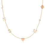A Custom Gold Necklace in rose gold with seven charms, pavé letters J and S, letters N and M, a heart, a birthstone and a pavé hand, on a white background.