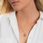 Close-up of a blonde woman wearing a Zodiac Necklace - Sagittarius with a white shirt against a neutral background. 