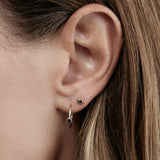 Close-up of a Birthstone Stud and Birthstone Hoop in Sapphire (September) in yellow gold in a brunette woman's ear. 